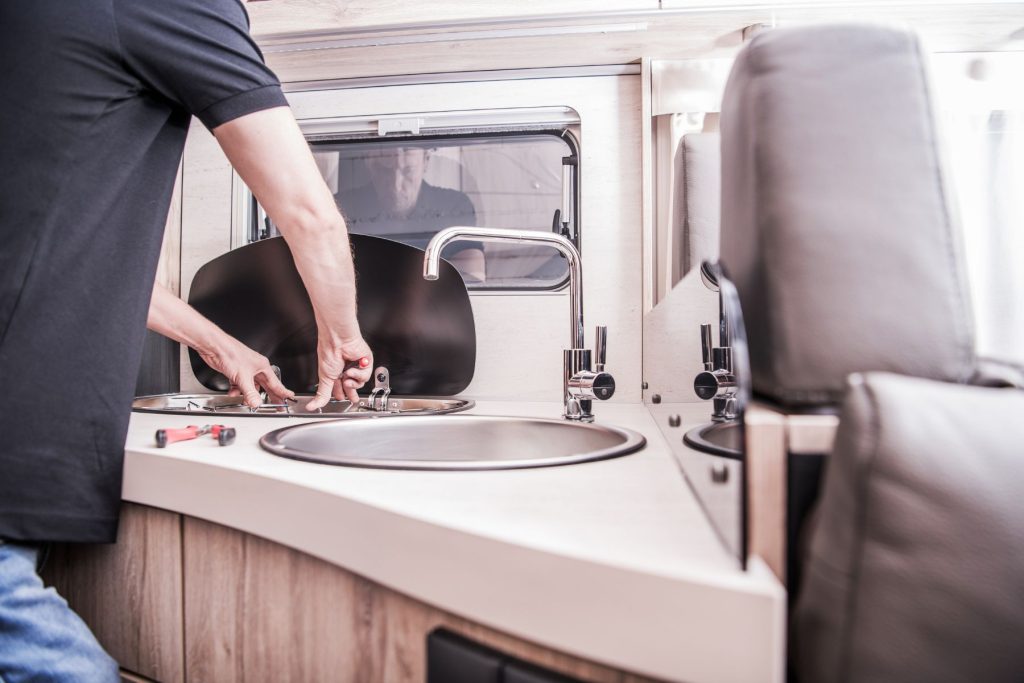 Man doing maintenance on the sinks in an RV